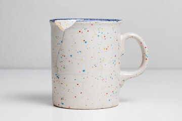 Broken mug on white table. Cracked cup