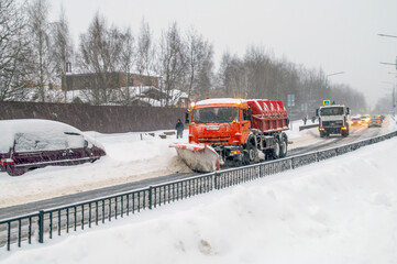 During a snowfall, two snowplows clear the roads