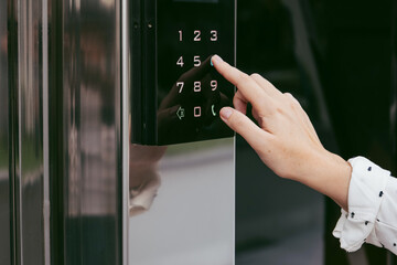Woman's hand using an intercom at entrance to building. Using an electronic lock