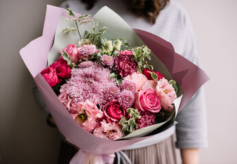 Very nice young woman holding big and beautiful bouquet of fresh roses, chrysanthemum, carnations, eustoma flowers in magenta pink colors, cropped photo, bouquet close up