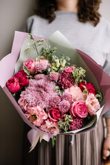 Very nice young woman holding big and beautiful bouquet of fresh roses, chrysanthemum, carnations, eustoma flowers in magenta pink colors, cropped photo, bouquet close up