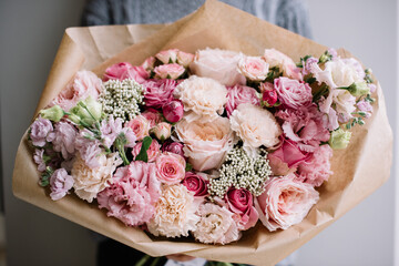 a young woman holding luxurious, huge and beautiful bouquet of fresh roses, carnations, eustoma, matthiola flowers in tender pink colors, cropped photo, bouquet close up - 555055626