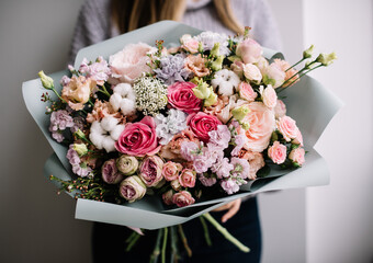 Very nice young woman holding big and beautiful bouquet of fresh tender roses, cotton, eustoma, matthiola flowers in pink colors, bouquet close up