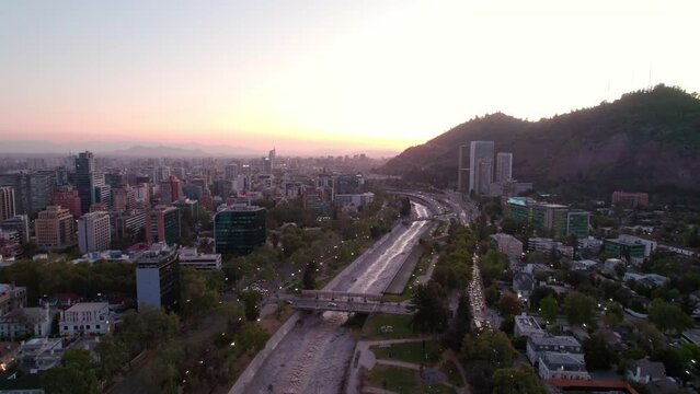 Nostalgic panoramic aerial view of the Mapocho river in Santiago, Chile with an orange sunset on the horizon.