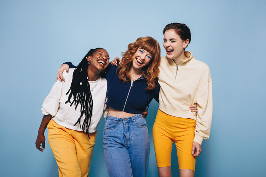 Group of young, diverse Gen Z women laugh and enjoy themselves in a vibrant studio setting, celebrating their friendship and good times
