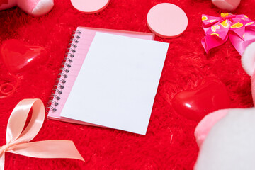 White blank notebook paper on the top of a pink notebook surrounded by valentine themed decorations