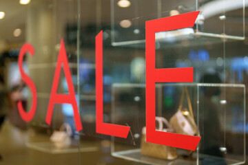 Annual clearance sale letters on a glass inside the popular clothing store. Selective focus image.