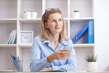 Young beautiful woman sitting in a chair and talking on the phone at her working place.