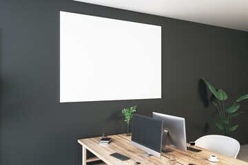 Perspective view on blank white poster with space for your logo or text on black wall background above light wooden work table with modern computers and office tools. 3D rendering, mock up