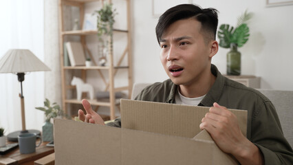 confused asian male shopper opening cardboard box feeling unhappy about the wrong online store...