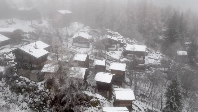 Snowy landscape with snowy chalets in the Swiss Alps. A mountain village in fog and snow