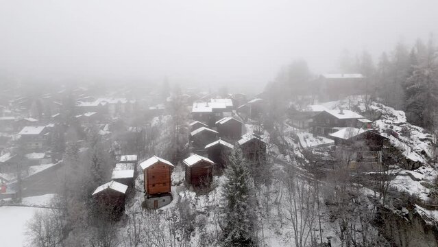Swiss mountain village Blatten Belalp with barns and huts in fog and snow. Snowy landscape with snowy cottages in Swiss Alps