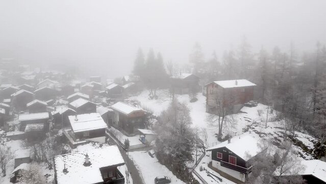 Snowy and snow-covered cottages in the Swiss Alps. The village of Blatten near Belalp in fog and snow