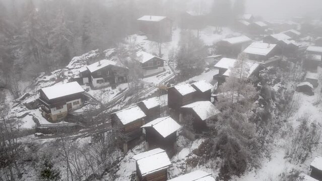 Snowy landscape with snowy cottages in the Swiss Alps. A mountain village in mist and snow