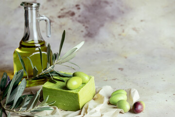 Traditional natural organic olive soap. Handmade soap bar with green olives, leaves and glass jar of olive oil on rustic background. Body care consept. Close up. Selective focus. Blurred background.