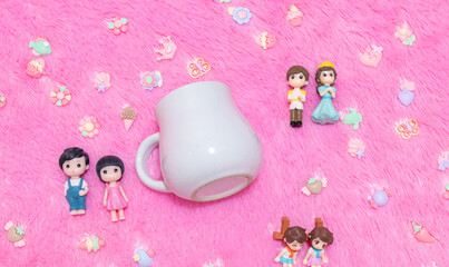 White blank milk mug on the top of a fluffy pink carpet surrounded by tiny lovely decorations