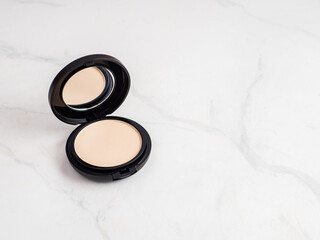 Compact powder on white marble, copy space