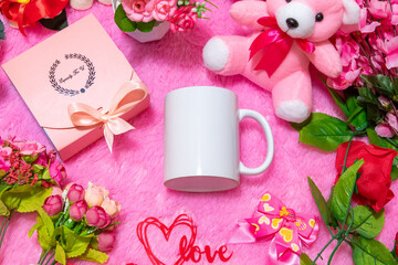 White blank coffee mug on the top of a fluffy pink carpet surrounded by valentine themed decorations