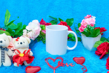 White blank coffee mug on the top of a fluffy blue carpet surrounded by valentine themed decorations