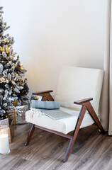 Christmas tree with presents and lights and chair in light and airy living room