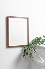 Blank photo frame mockup on white wall with natural eucalyptus plant, scandinavian style interior