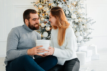 Cheerful man and woman opening a Christmas present