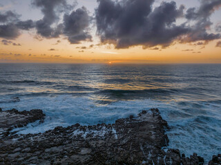 Fototapeta premium Surfs up sunrise at the seaside with scattered clouds