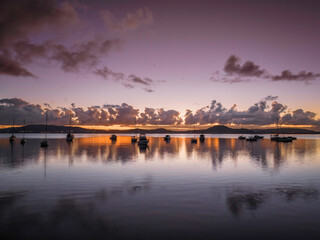 Fototapeta premium Aerial sunrise waterscape with boats, clouds and reflections