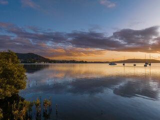 Aerial sunrise waterscape with boats, clouds and reflections