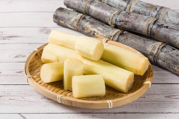 fresh sugarcane with cut pieces on wooden table