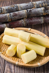 fresh sugarcane with cut pieces on wooden table