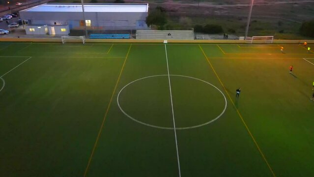 Backwards revealing drone shot of a football field during golden hour flying over the middle line in Santa Ponsa, Mallorca, Spain.