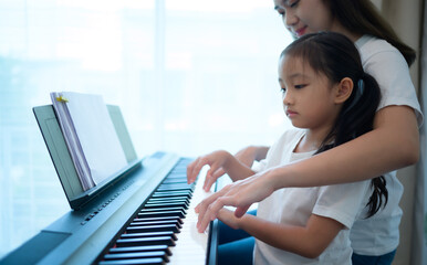Fototapeta premium Family vacation, other helping daughter practice in her piano lessons