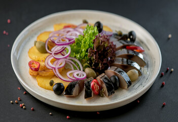 Composition of salted mackerel with garnish, potatoes, onions, served on a wooden board,