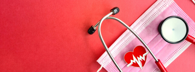 Stethoscope protective mask and heart cardiogram sign on red background