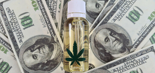 Dollars and marijuana oil in vial. Earnings and income cannabis
