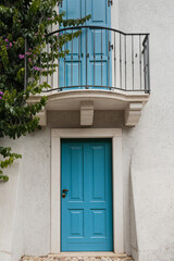 Old historic Italian architecture. Blue wooden door, balcony, blooming bush, pastel walls