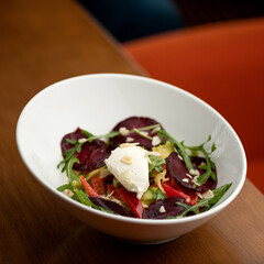 Portion of salad with beets, peppers, arugula, lettuce and cream cheese in white plate. Healthy lifestyle. Healthy nutrition. Top view. Vegetarian food. Close-up. Soft focus.