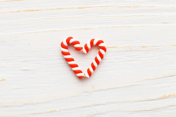 Christmas composition with candy canes in the form oh heart on light blue wooden background