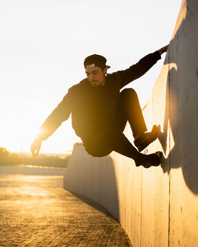 Guy doing parkour and breakdancing tricks at sunset in the street