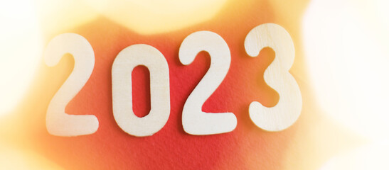 wooden number 2023 on christmas shiny gold and red background. sparkle festive blurred bokeh