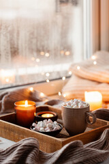 Fototapeta na wymiar warm cozy window arrangement, winter or autumn concept, coffe, candles throw lights
