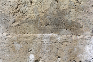 A stone plastered surface with damages. Beige background texture. An old weathered wall with detailed texture.