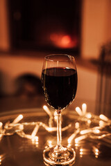 A glass of red wine on a glass table near the fireplace. Christmas Eve