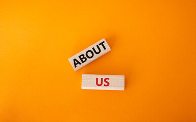 About us symbol. Wooden blocks with words About us. Beautiful orange background. Business and About us concept. Copy space.