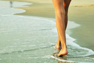 Feet on the beach near the sea.
