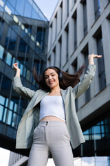 Buisness woman sfter hard day work standing on buisness centre background dancing while listening to music through headphones earbuds of latest series.