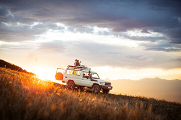 People watching sunset on top of 4x4 vehicle in Mountains of Goden, Kosovo - obrazy, fototapety, plakaty