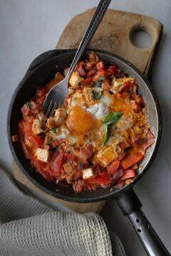 Shakshuka homemade variation with egg, tomato, on an a iron pan on a marble background. Top view.