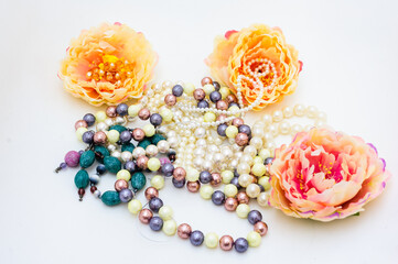 Multi-colored beads among artificial yellow blossoming peonies. 